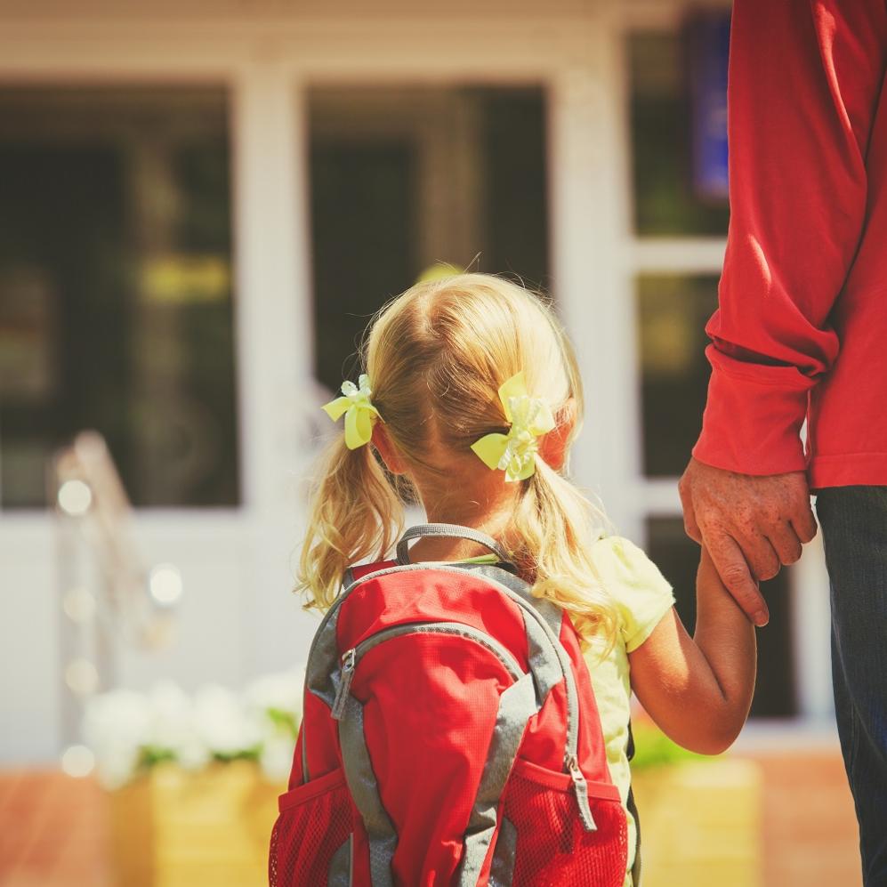 Kindergartenkind wird an der Hand zur Kita gebracht